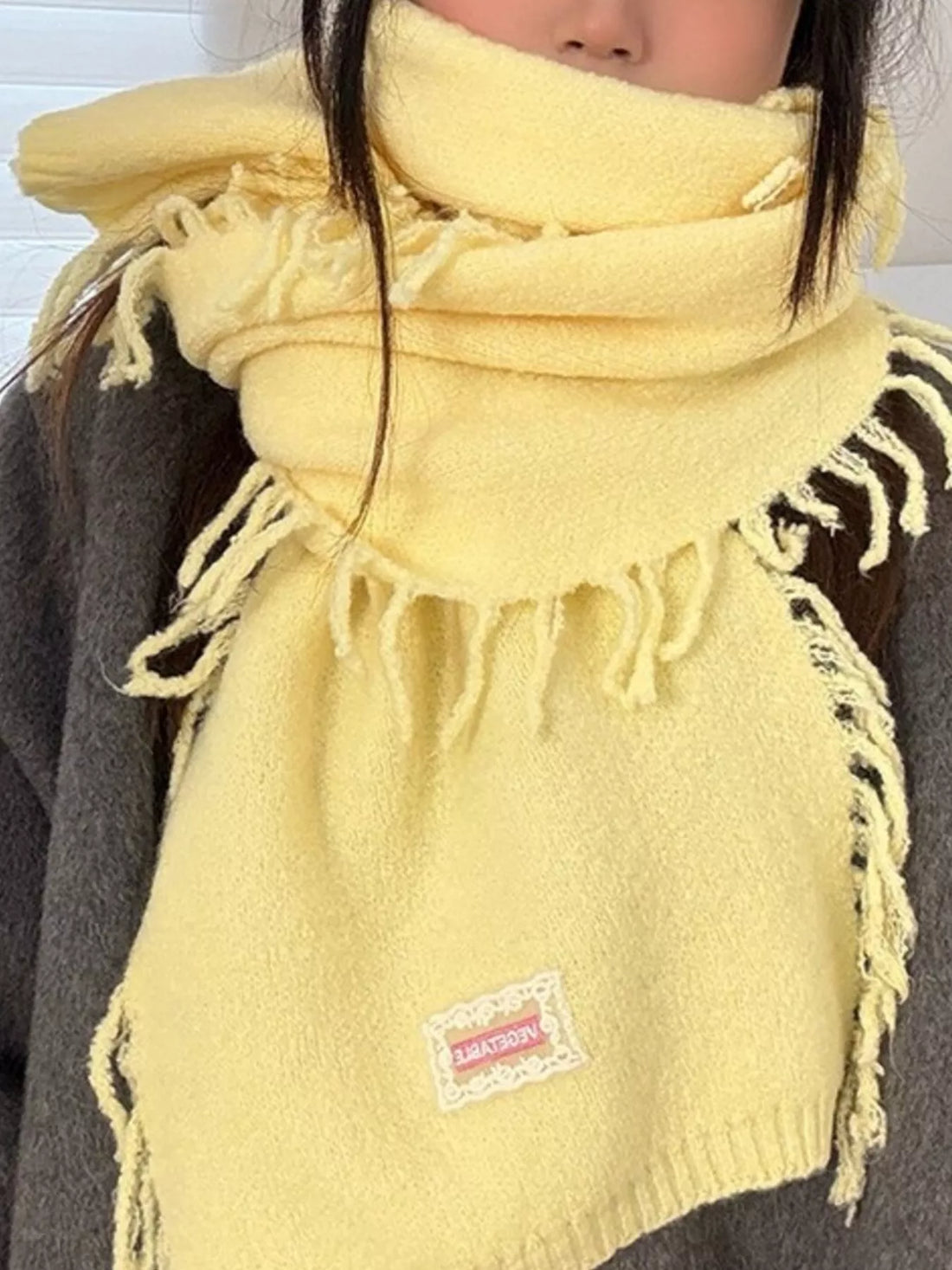 Elegant woman wearing luxurious knitted fringe scarf - winter fashion styling guide