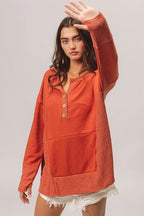 Woman wearing an orange long-sleeve shirt with a plain background