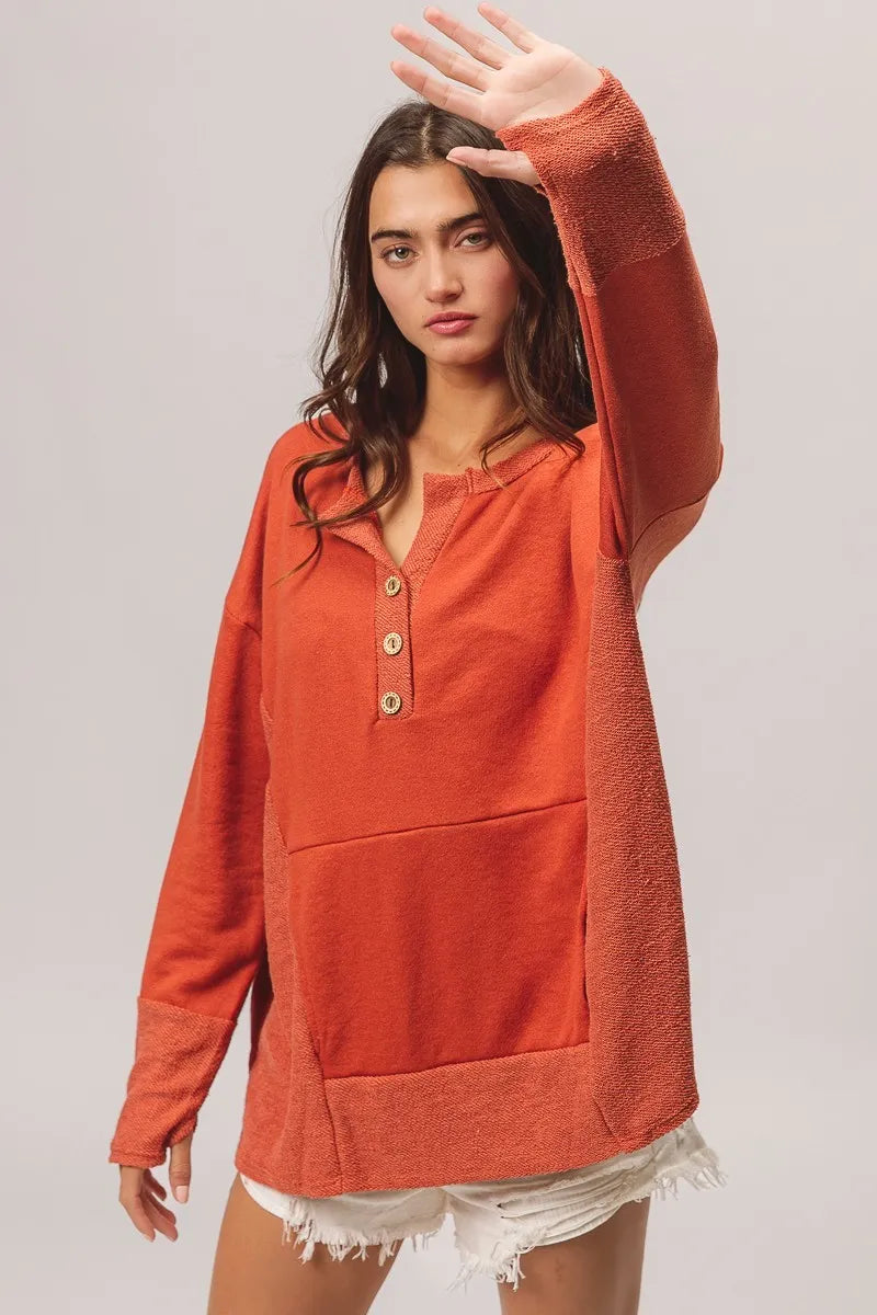 Woman wearing an orange long-sleeve shirt with a plain background